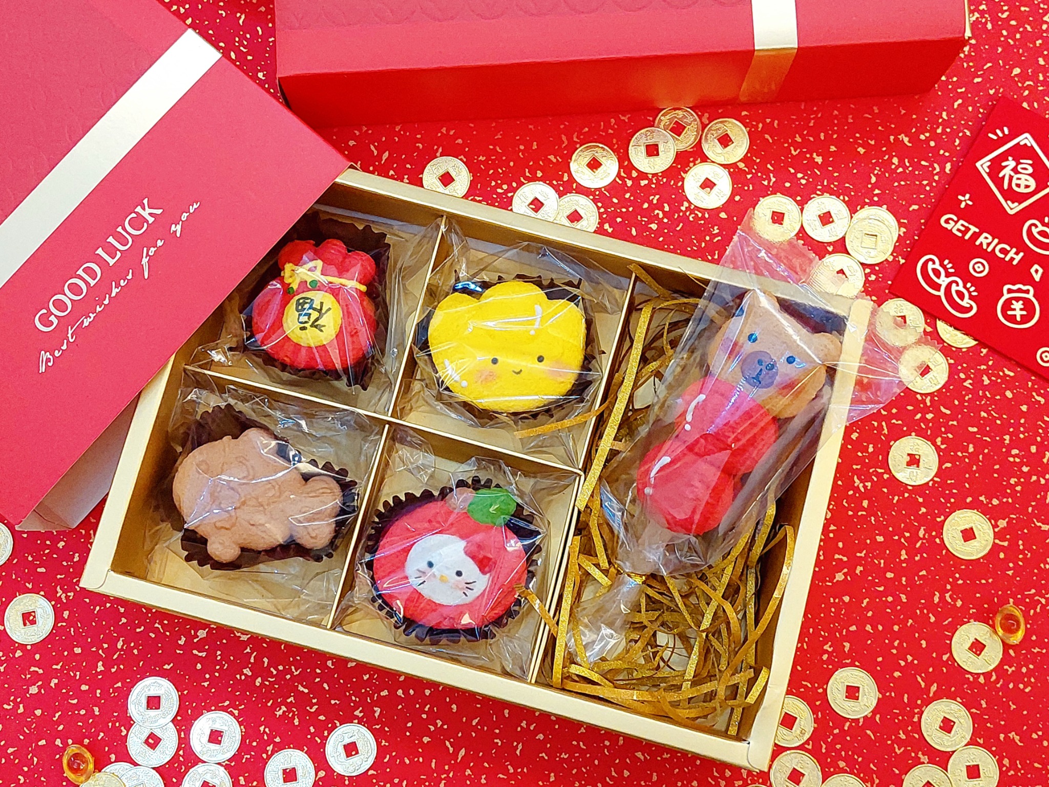 紅金色新年禮盒與 GOOD LUCK 卡片，盒中有多款節慶造型甜點